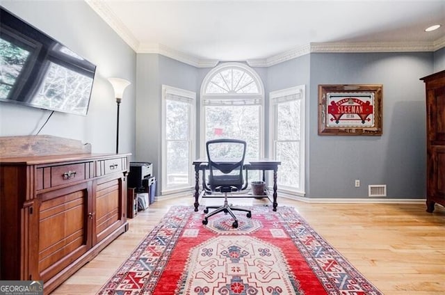 home office featuring a wealth of natural light, visible vents, light wood-type flooring, and ornamental molding