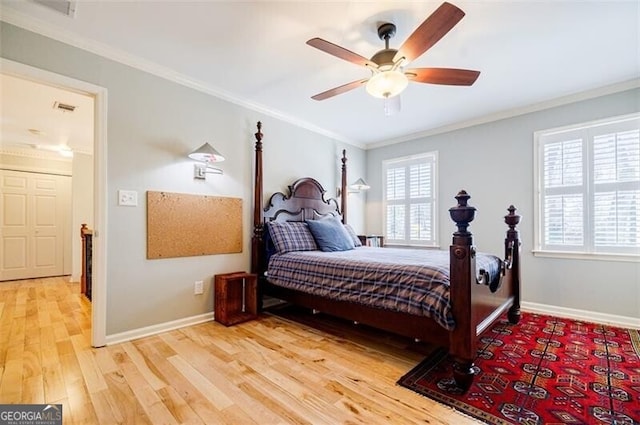 bedroom featuring baseboards, crown molding, and light wood finished floors