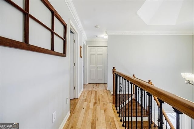 hallway featuring crown molding, an upstairs landing, light wood-type flooring, and baseboards