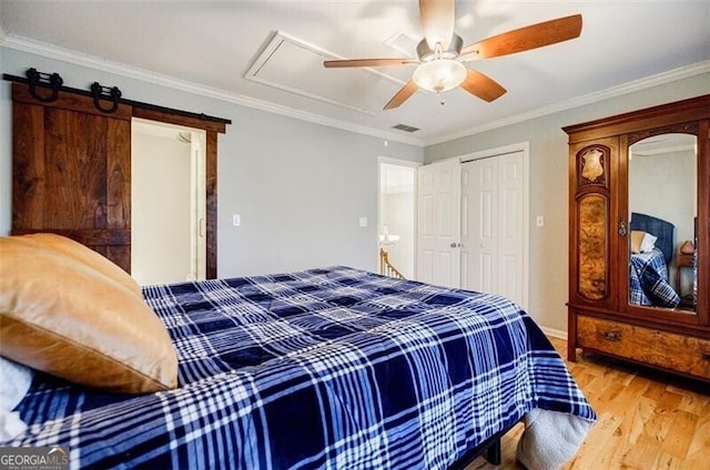 bedroom with visible vents, crown molding, attic access, wood finished floors, and a ceiling fan