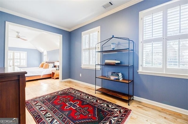 bedroom with visible vents, crown molding, baseboards, and wood finished floors