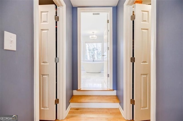 corridor featuring light wood-type flooring and baseboards