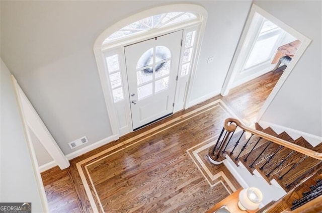 foyer with a wealth of natural light, visible vents, baseboards, and stairway