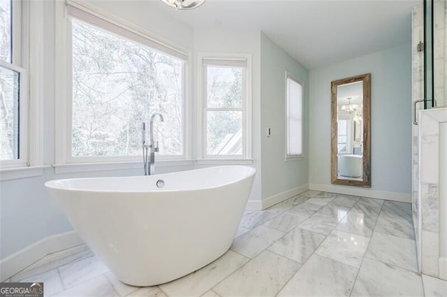 full bathroom featuring baseboards, a freestanding bath, and marble finish floor