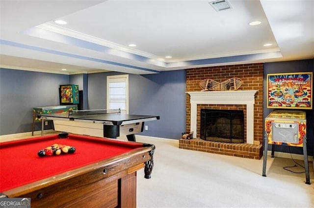 recreation room featuring visible vents, carpet floors, a fireplace, ornamental molding, and a raised ceiling