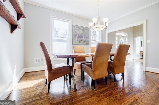 dining area with visible vents, ornamental molding, wood finished floors, baseboards, and a chandelier