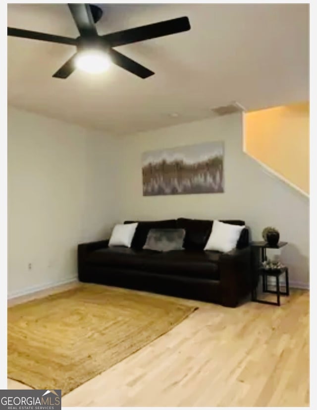 living room with baseboards, a ceiling fan, and wood finished floors