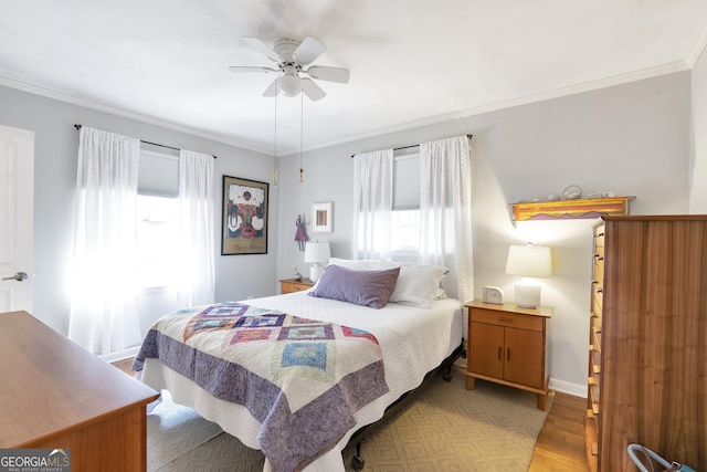 bedroom with light wood finished floors, multiple windows, and crown molding