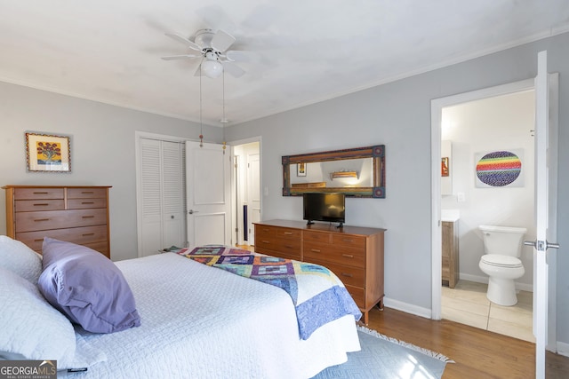 bedroom with baseboards, ensuite bath, wood finished floors, crown molding, and a closet