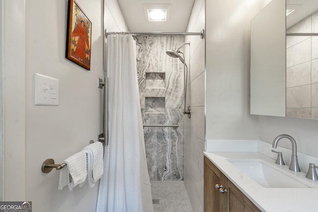 bathroom with a tile shower and vanity