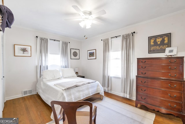 bedroom with ornamental molding, wood finished floors, and visible vents