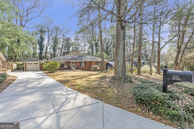 view of front facade featuring driveway, an outdoor structure, and brick siding