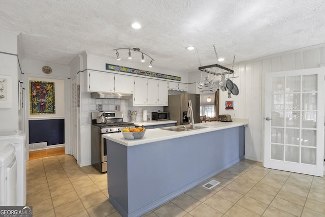 kitchen with under cabinet range hood, stainless steel appliances, a sink, visible vents, and washing machine and clothes dryer