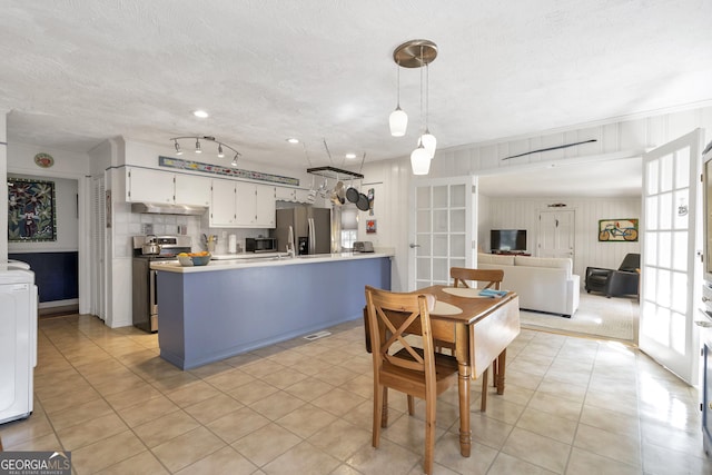 kitchen featuring tasteful backsplash, appliances with stainless steel finishes, a peninsula, light countertops, and a textured ceiling