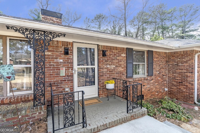 property entrance with brick siding and a chimney