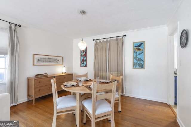 dining area with light wood-style floors, baseboards, and crown molding