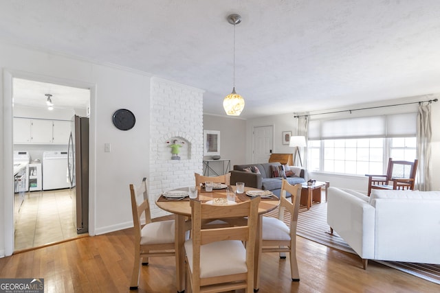 dining space with light wood-style floors, washing machine and dryer, baseboards, and crown molding