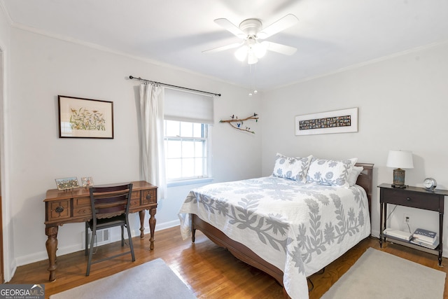 bedroom with ceiling fan, crown molding, baseboards, and wood finished floors