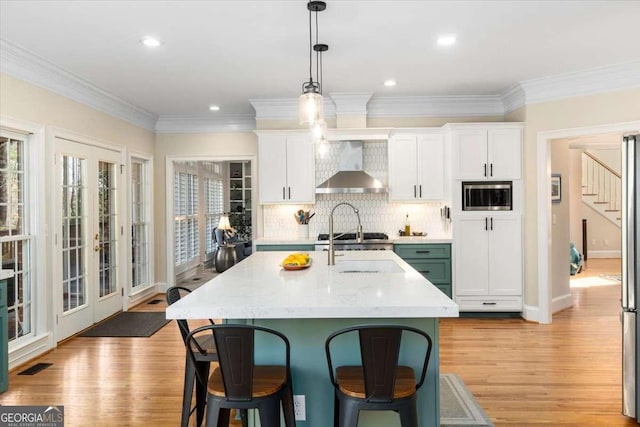 kitchen featuring light wood-type flooring, a kitchen breakfast bar, and wall chimney exhaust hood