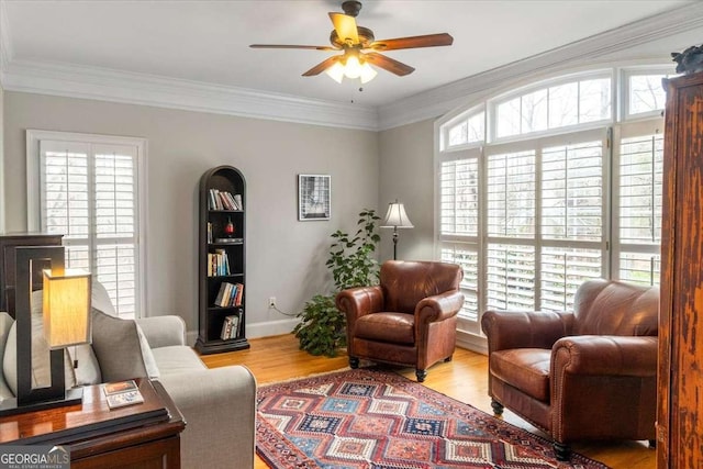 sitting room with a ceiling fan, crown molding, baseboards, and wood finished floors