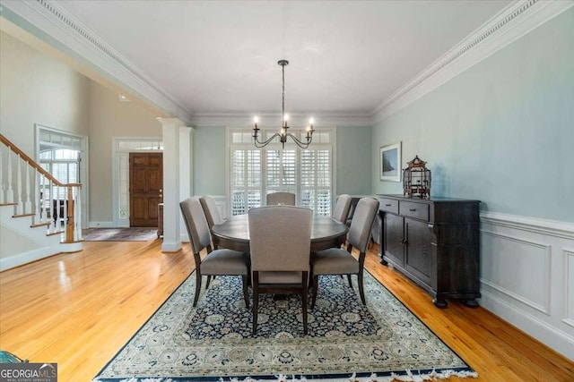 dining space with crown molding, light wood finished floors, decorative columns, and a healthy amount of sunlight