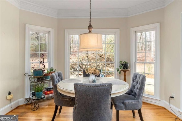 dining area with ornamental molding, light wood-type flooring, and baseboards