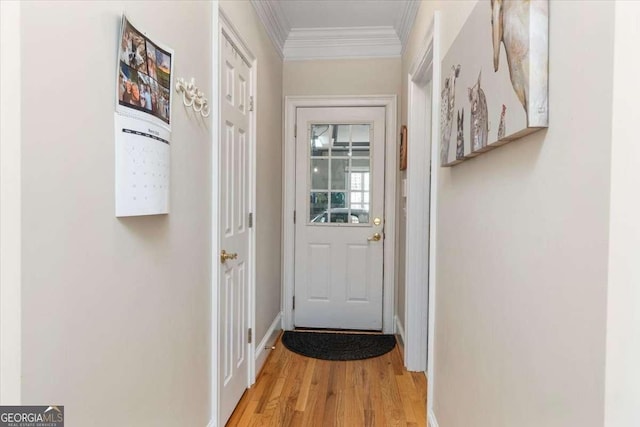 doorway featuring baseboards, light wood-type flooring, and crown molding