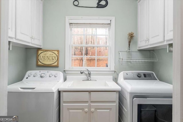 clothes washing area featuring cabinet space, a sink, and washing machine and clothes dryer