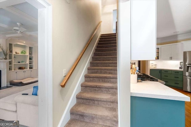 stairway with a fireplace with flush hearth, baseboards, ceiling fan, and crown molding