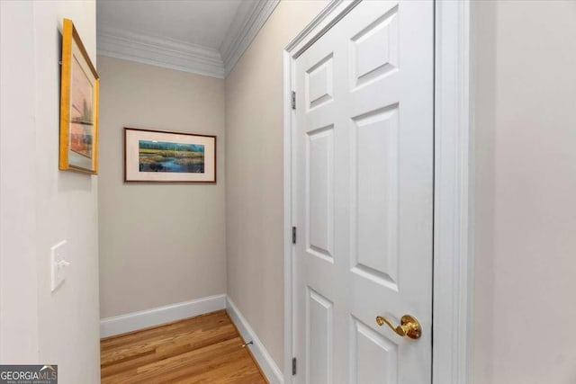 hallway featuring light wood-style floors, ornamental molding, and baseboards