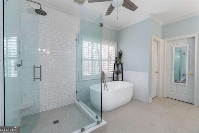 full bathroom featuring a stall shower, ornamental molding, tile patterned flooring, a freestanding tub, and tile walls