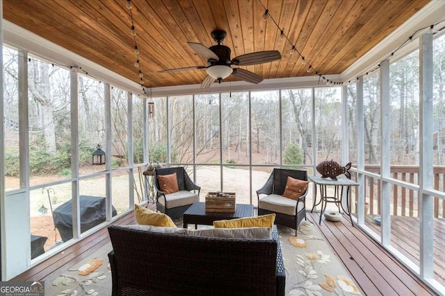 sunroom featuring plenty of natural light, wooden ceiling, and a ceiling fan