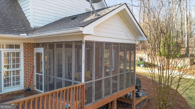 exterior space featuring a shingled roof, a sunroom, and brick siding