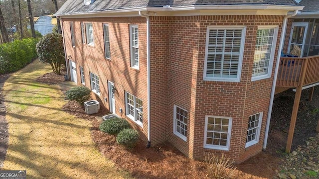 view of property exterior featuring central air condition unit, a shingled roof, a garage, and brick siding