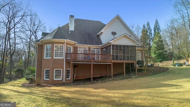 rear view of property with a sunroom, brick siding, a lawn, and a chimney