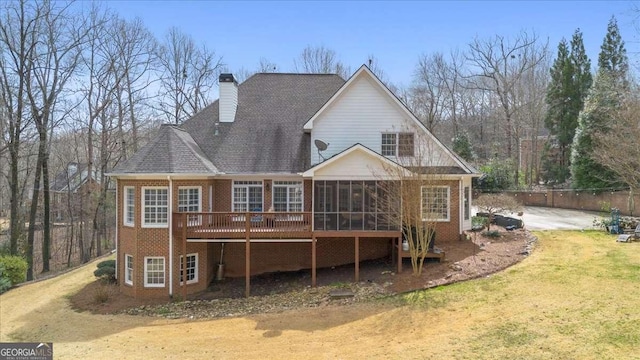 back of house with a sunroom, brick siding, a yard, and a chimney