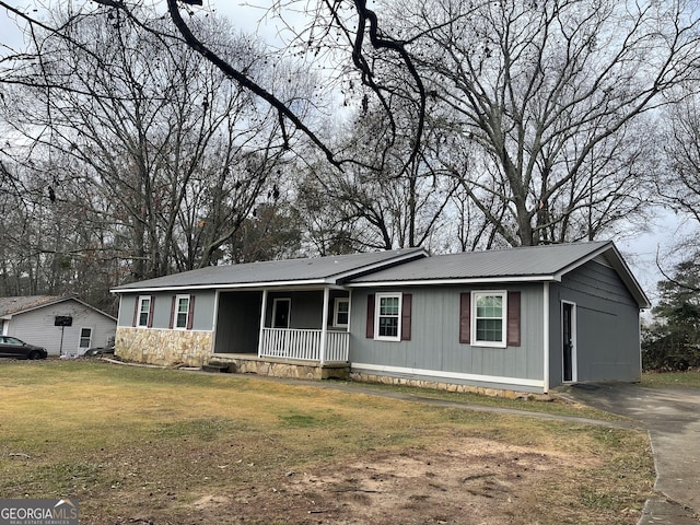 ranch-style home with covered porch, metal roof, and a front lawn