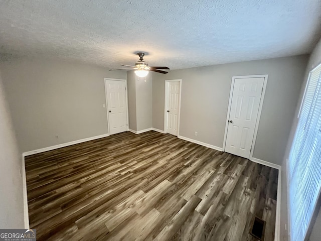 unfurnished bedroom with a textured ceiling, a ceiling fan, baseboards, and dark wood-style flooring