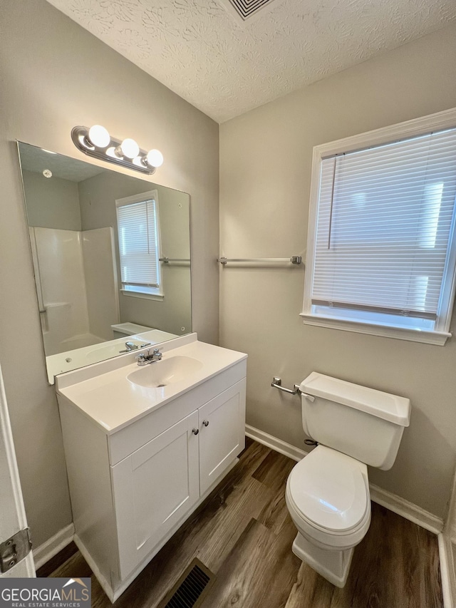bathroom with toilet, a textured ceiling, baseboards, and wood finished floors