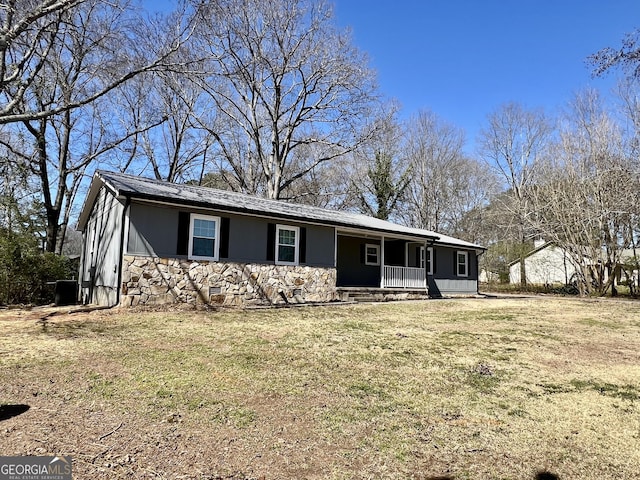 single story home featuring stone siding, covered porch, and a front yard