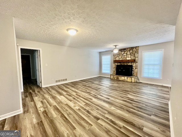 unfurnished living room featuring visible vents, baseboards, a fireplace, wood finished floors, and a ceiling fan