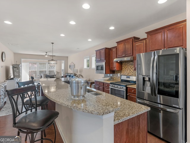 608 Larch Looper Dr, Griffin, GA 30223 - kitchen with light stone counters, stainless steel appliances, open floor plan, under cabinet range hood, and tasteful backsplash