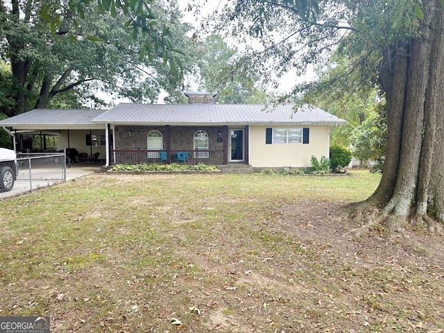 ranch-style home featuring a front yard, covered porch, metal roof, and an attached carport