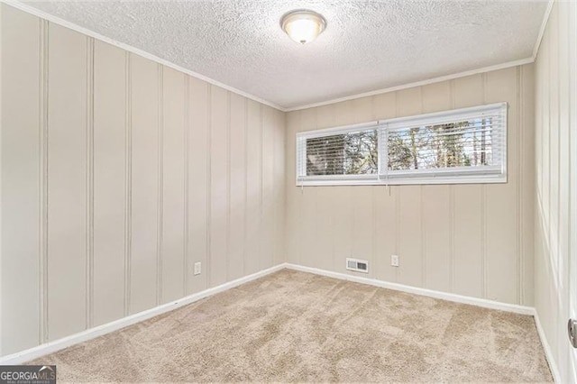 spare room featuring carpet, visible vents, crown molding, and a textured ceiling