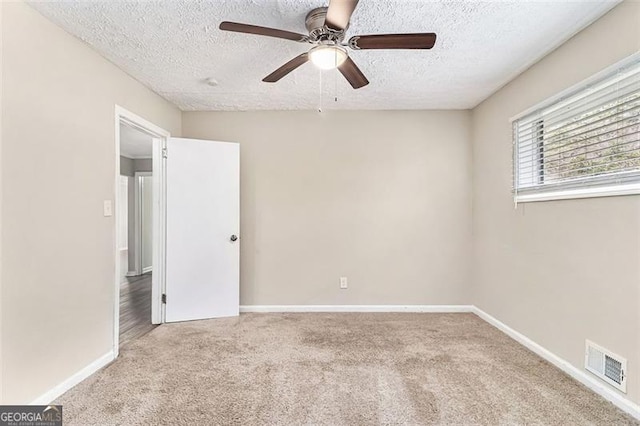 unfurnished room featuring carpet floors, baseboards, visible vents, and a textured ceiling