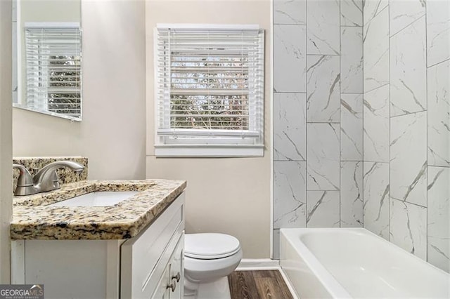 full bathroom with toilet, wood finished floors, vanity, baseboards, and  shower combination