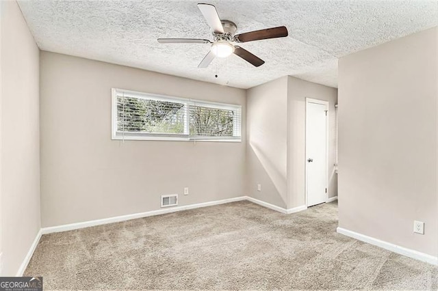 carpeted empty room featuring baseboards, a textured ceiling, visible vents, and a ceiling fan