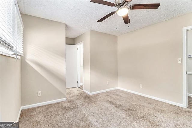 unfurnished room with a textured ceiling, carpet floors, ceiling fan, and baseboards