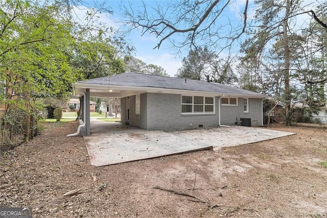 back of house with crawl space, dirt driveway, an attached carport, and brick siding