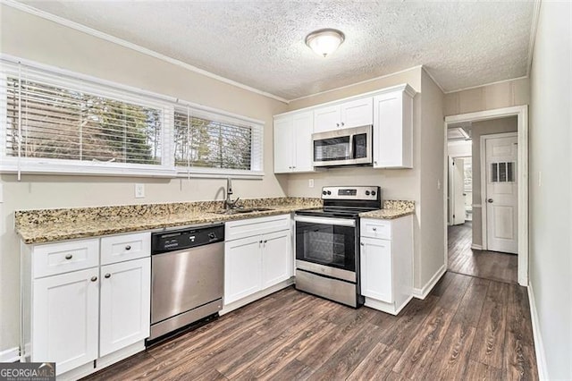 kitchen with dark wood-type flooring, a sink, white cabinets, appliances with stainless steel finishes, and light stone countertops